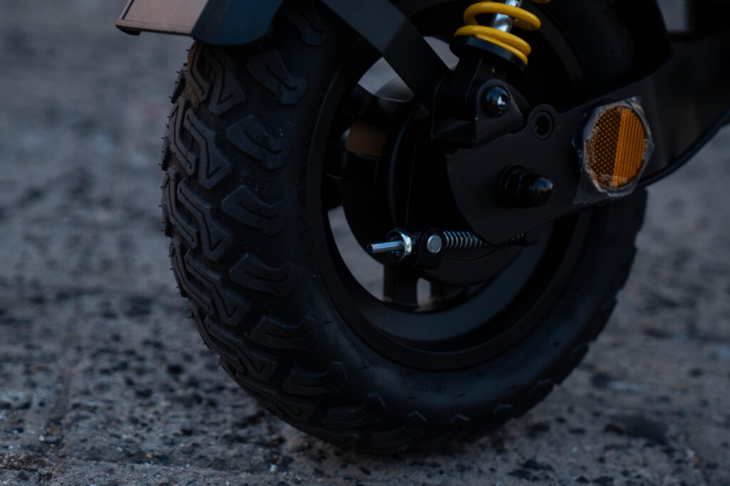 Close-up of a Speedbike scooter's front wheel and yellow suspension spring